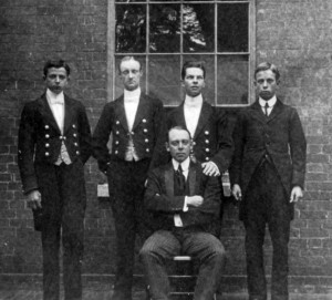 Denbies footmen in their livery of chocolate with red piping. The brass buttons bear the Cubitt crest and a coronet. The seated man may be the underbutler, or the butler, although the familiarity of a footman's hand on his shoulder makes this latter suppostion doubtful (Ranmore Archive)